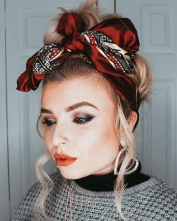 Woman with a high messy bun wrapped in a red patterned silk scarf.