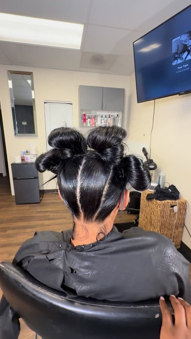 Black hair styled into four rounded space buns in a salon setting.
