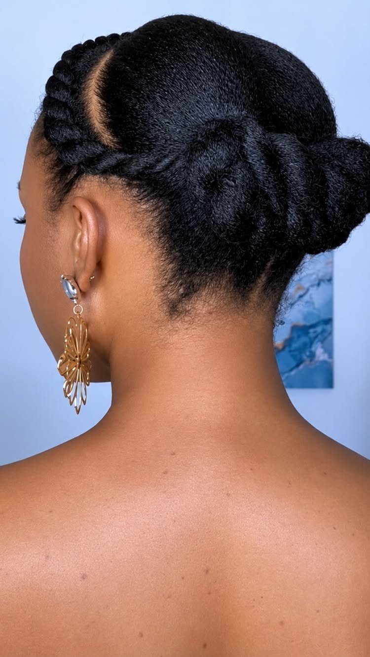 Woman with black hair in a low twisted bun and side braid.