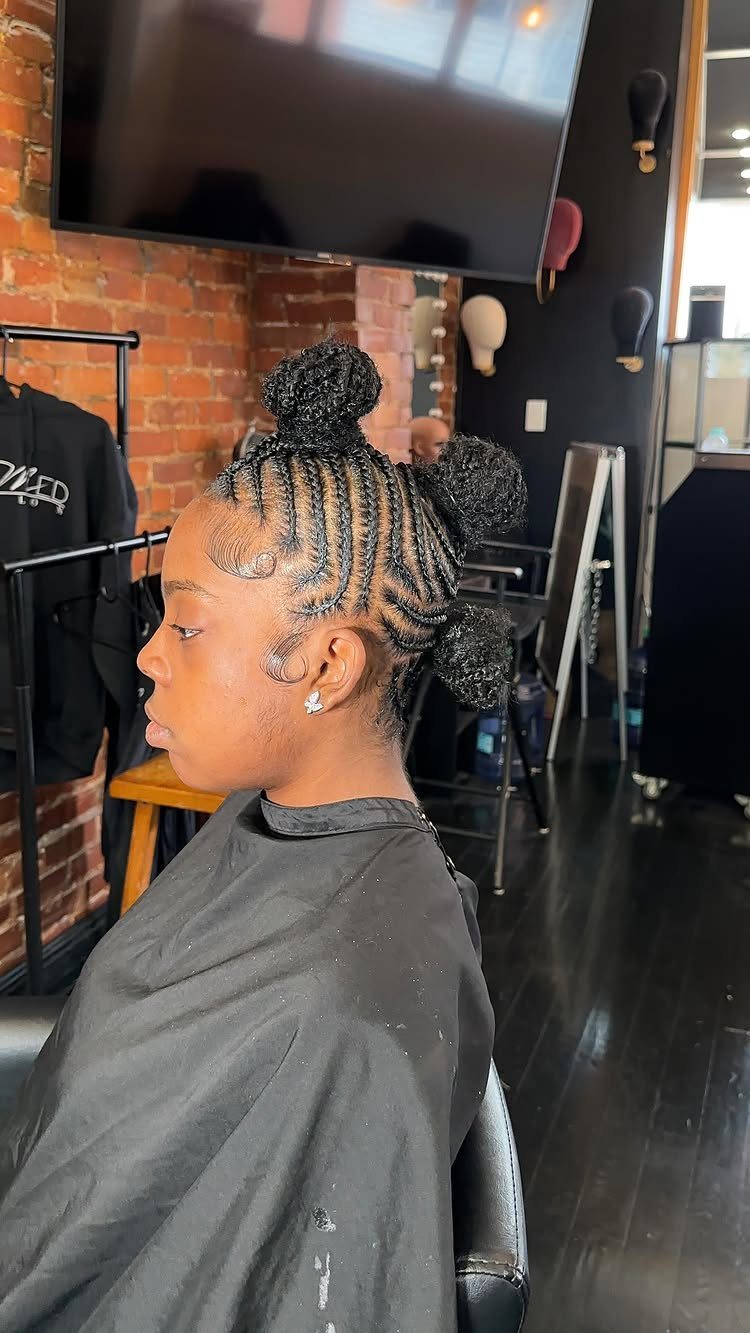 Woman with cornrow braids styled into three small buns in a mohawk shape.