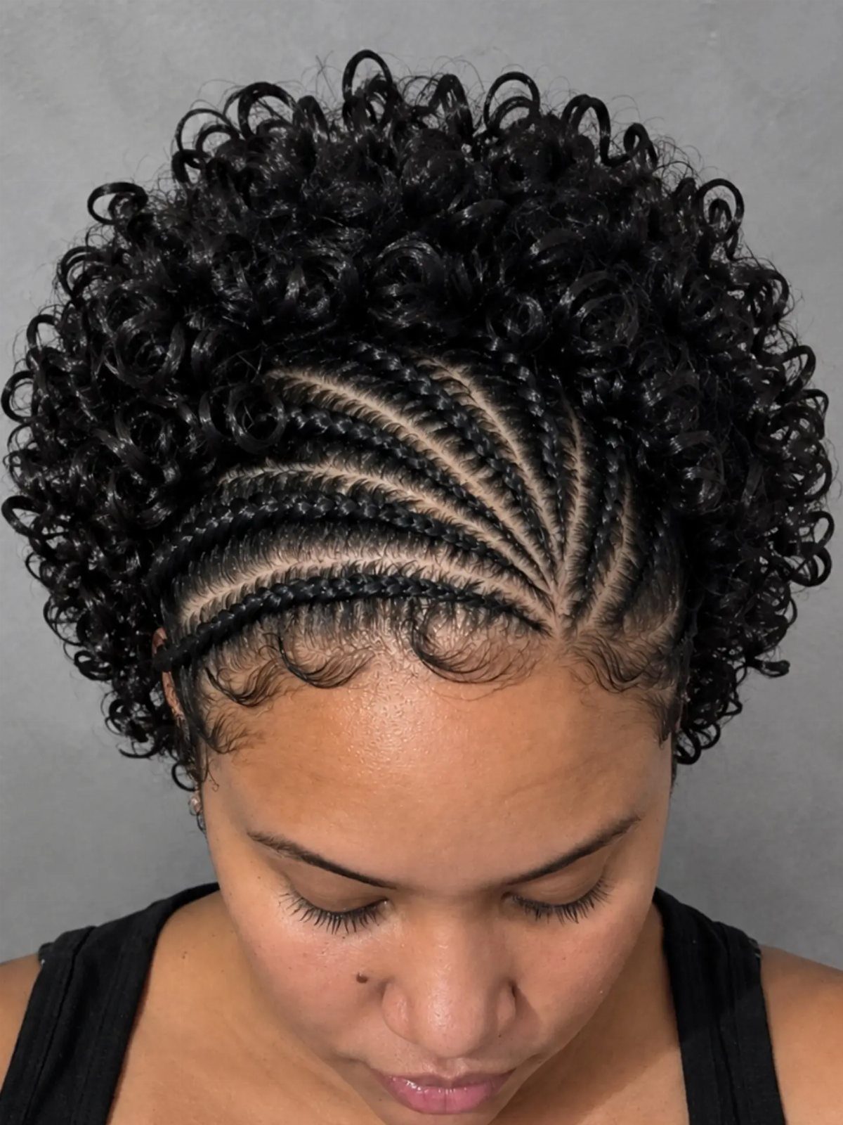 Woman with black hair styled in cornrows and a curly updo.