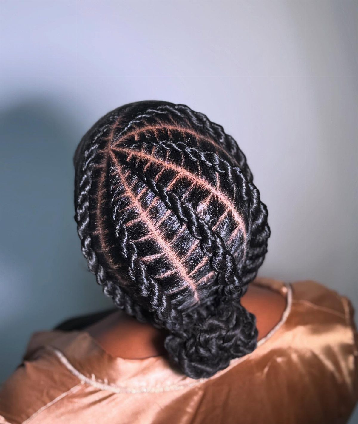 Black hair styled in flat twists gathered into a low bun at the nape.