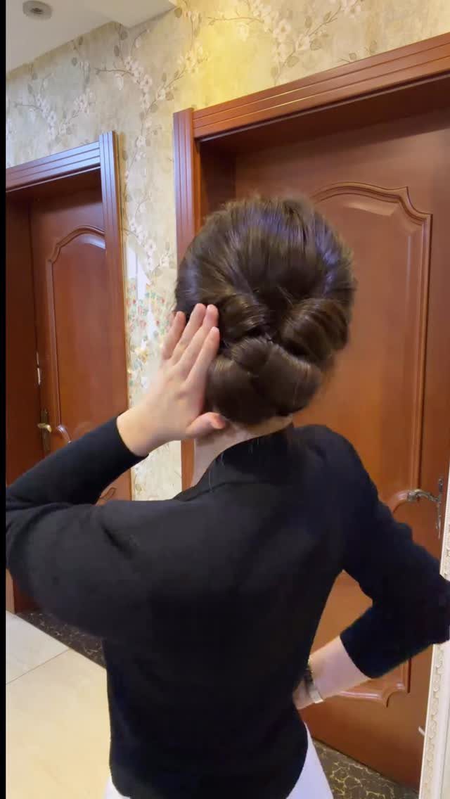 Woman with a polished, shiny brown low updo in a formal setting.