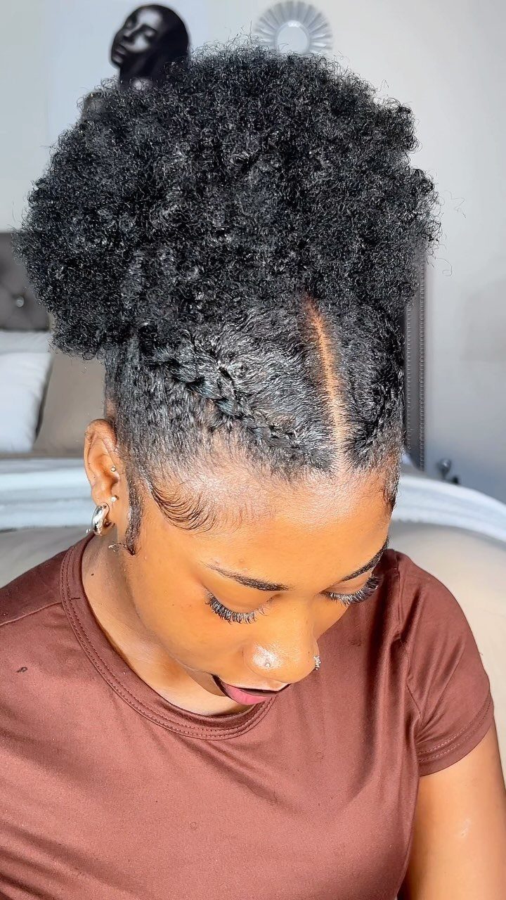 Woman with a high, voluminous afro puff updo and sleeked back edges.