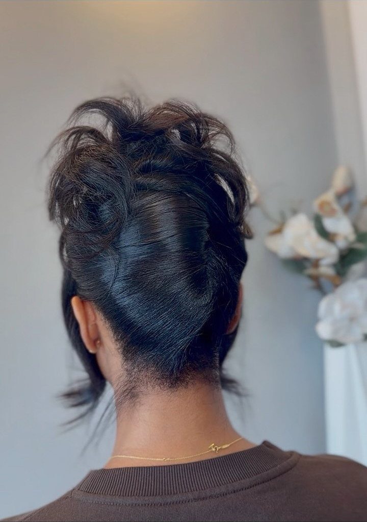 Black hair styled in a textured pinned updo seen from the back.