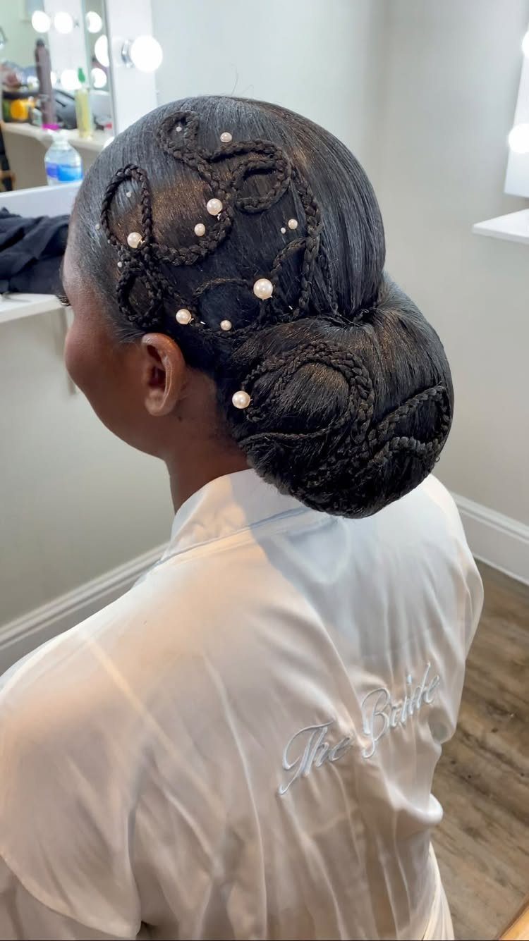 Woman with a rolled black hair updo adorned with small white pearl pins.