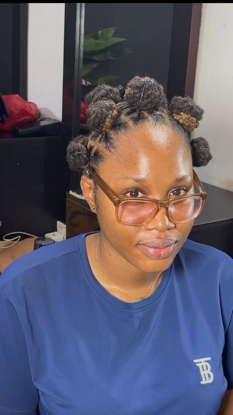 Woman with brown glasses wearing her hair in several small Bantu knots.