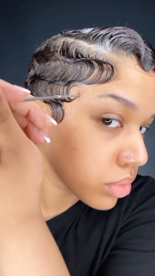 Person with short dark hair styled in glossy finger waves being combed.