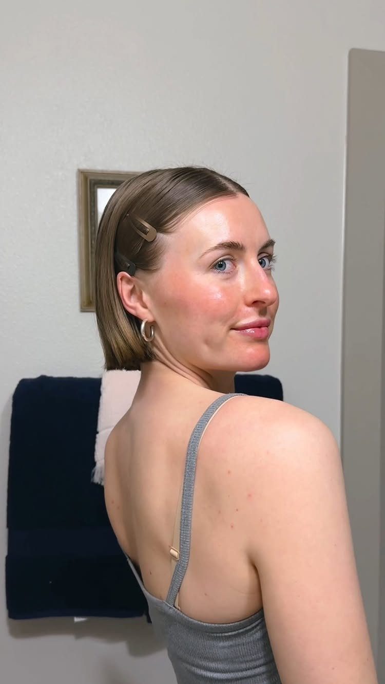 Woman with short blonde hair slicked back and secured with a hair clip.