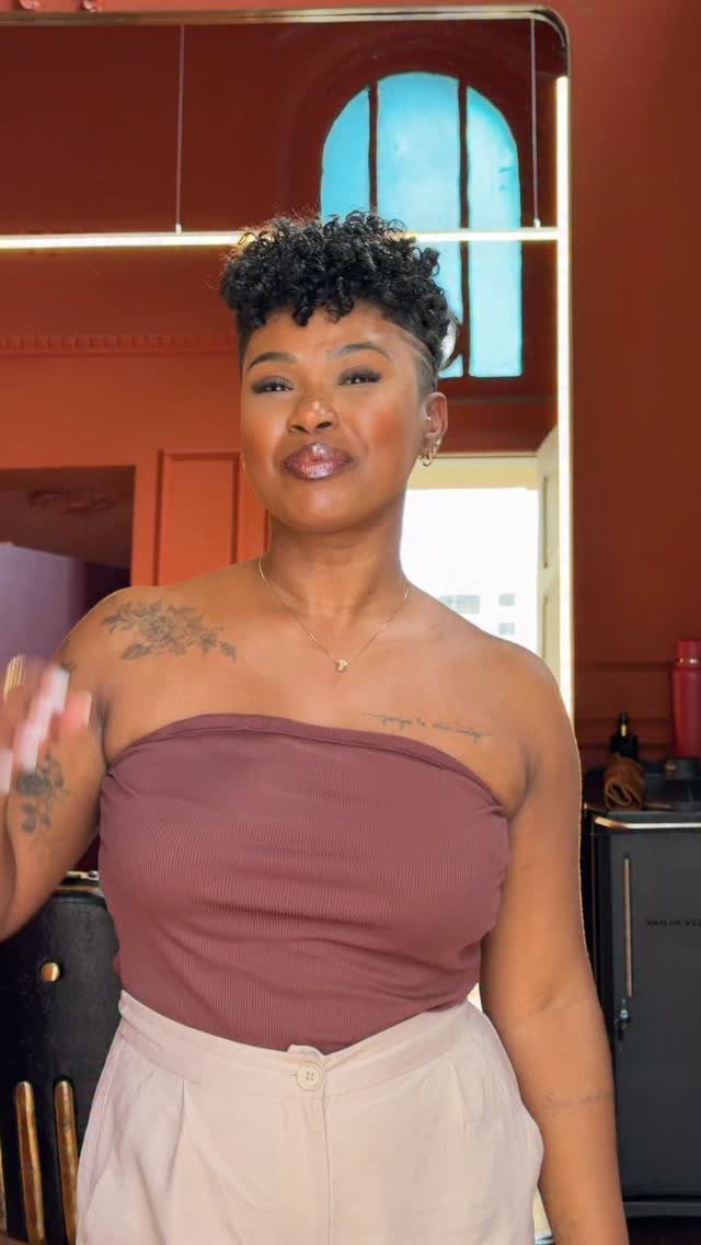 Woman with a tapered natural haircut featuring short sides and curly top hair.