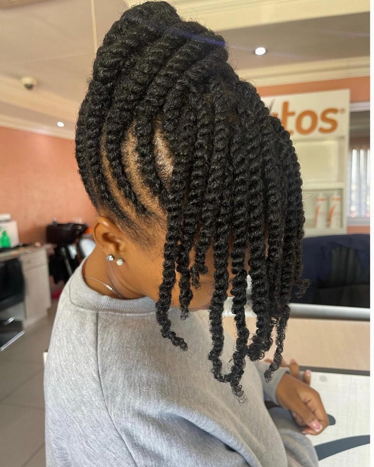 Person with black twisted hair gathered into a high curly updo style.