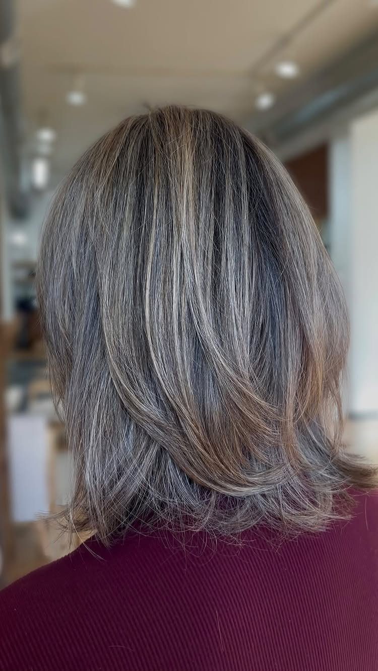 Ash-brown hair with blonde highlights in a layered medium-length cut from behind.
