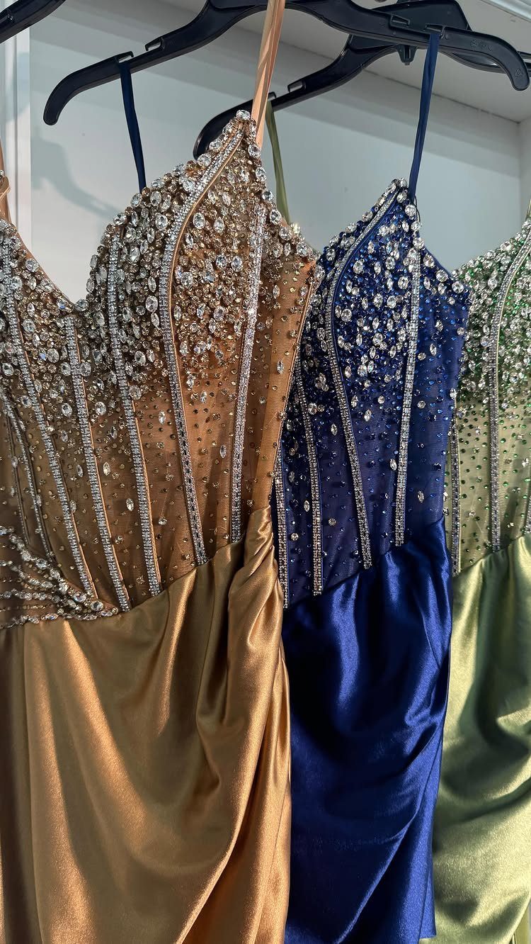 10 Nice Prom Dresses for Every Style and Body Type 8 Three formal gowns in gold, navy, and green with beaded bodices on hangers.