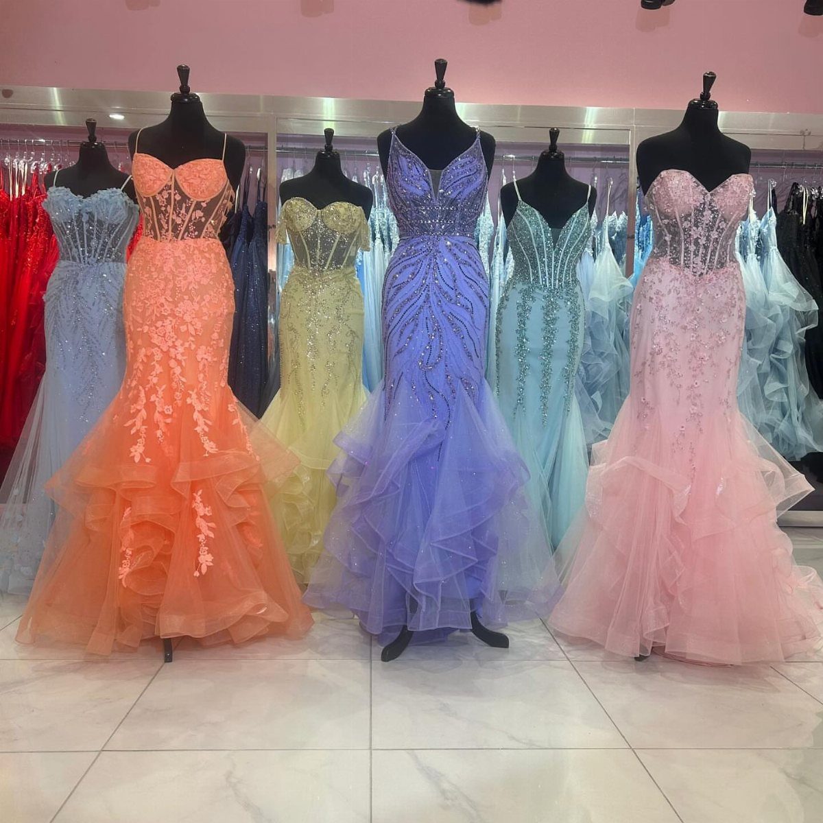 10 Nice Prom Dresses for Every Style and Body Type 2 Colorful mermaid-style prom dresses on mannequins in a brightly lit clothing boutique.