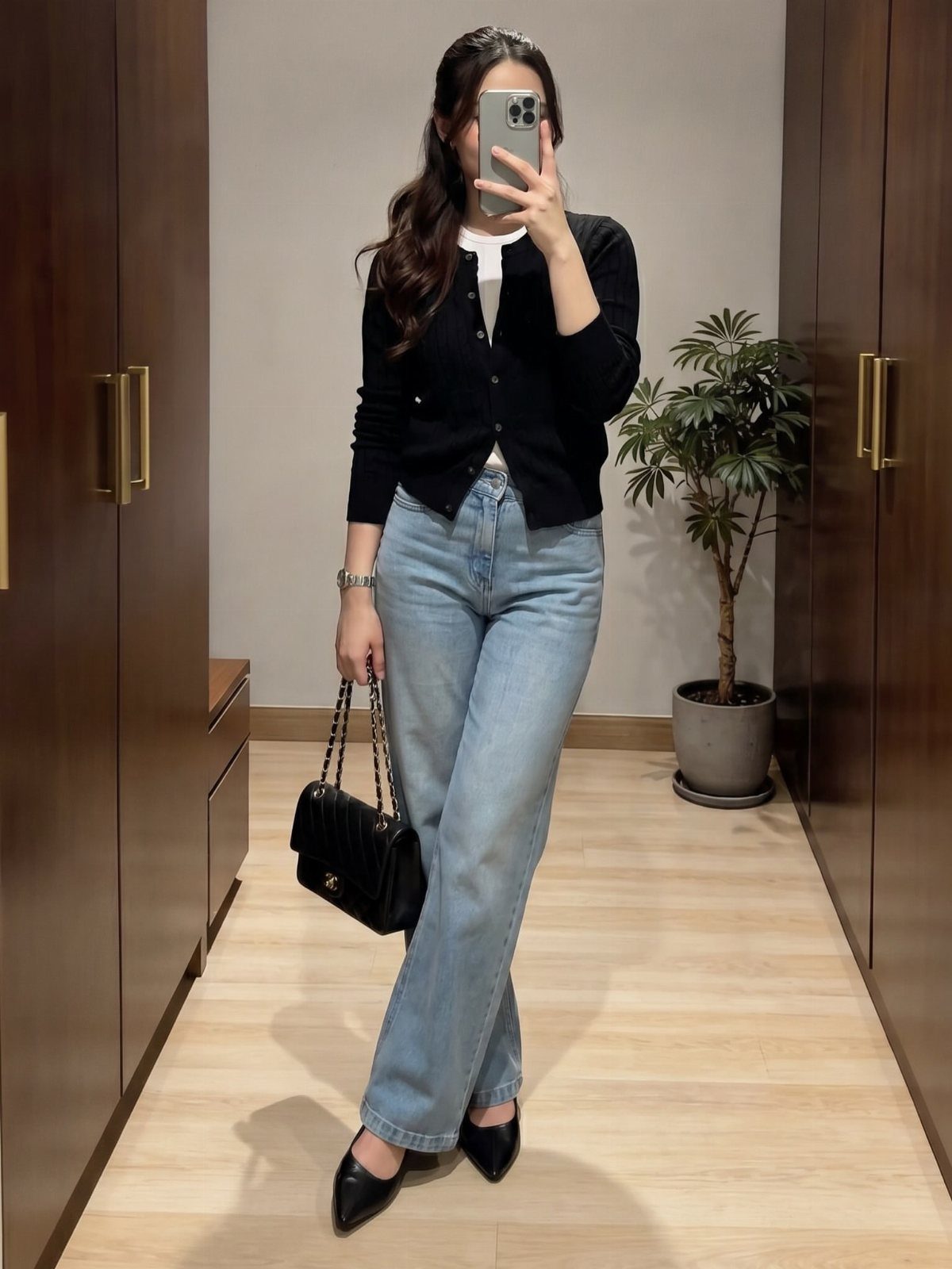 Woman wearing a black cardigan, white top, and light-wash straight-leg jeans with flats.