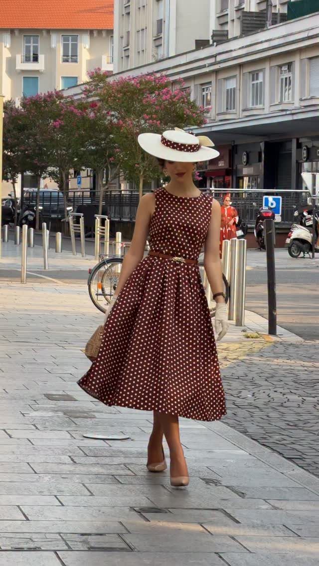 Old Fashion Designers and 3 Ideas They Made Classic 3 Woman in a brown polka-dot high-waisted dress and matching hat walking outdoors.