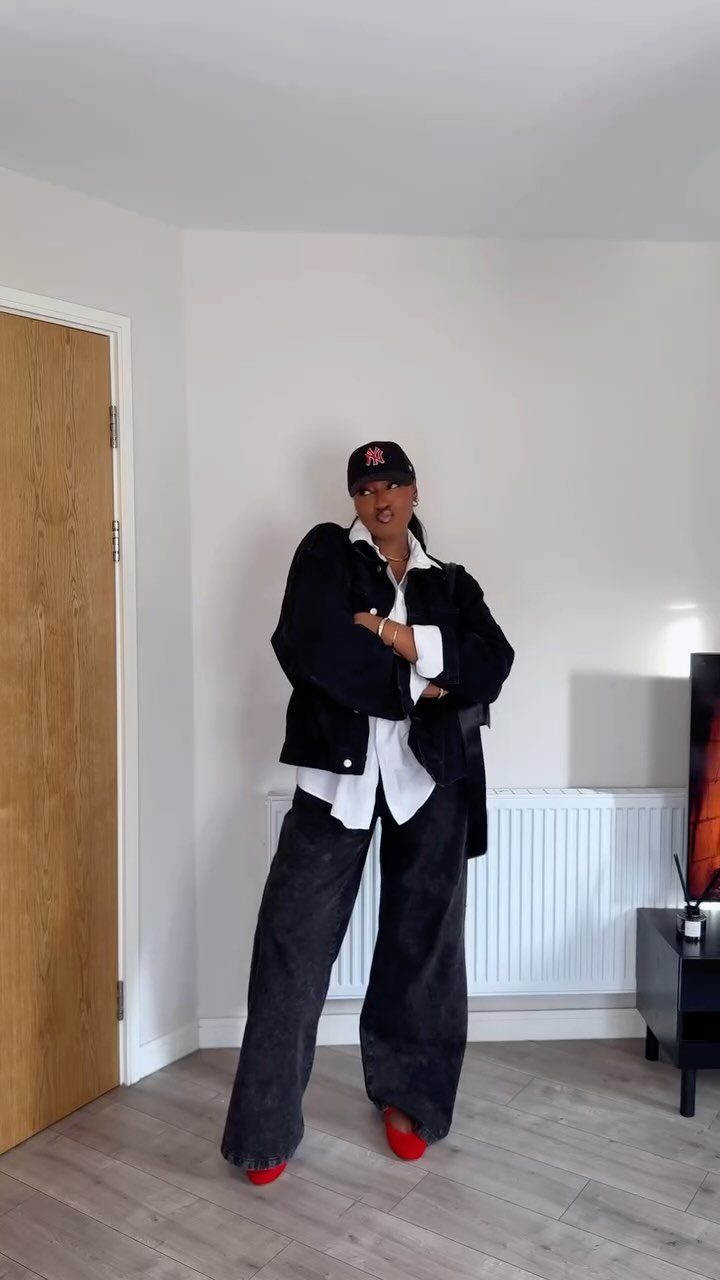 Person wearing a black jacket, white shirt, wide-leg trousers, and red shoes.