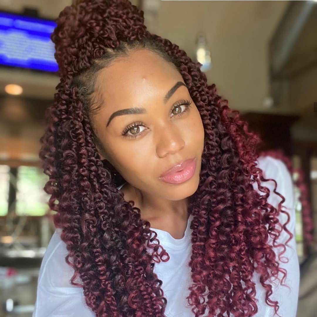 Woman with burgundy passion twists styled in a half-up half-down top bun.