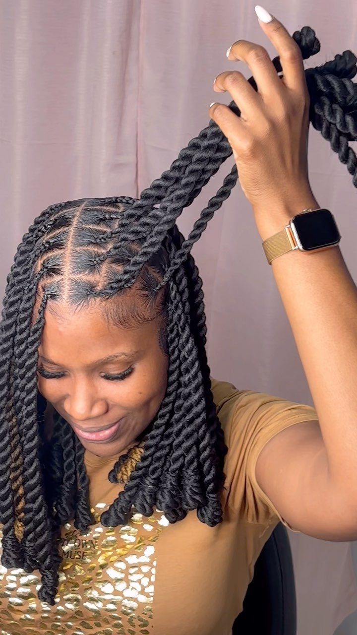 Woman with black passion twist bob hairstyle wearing a gold shirt and smartwatch.