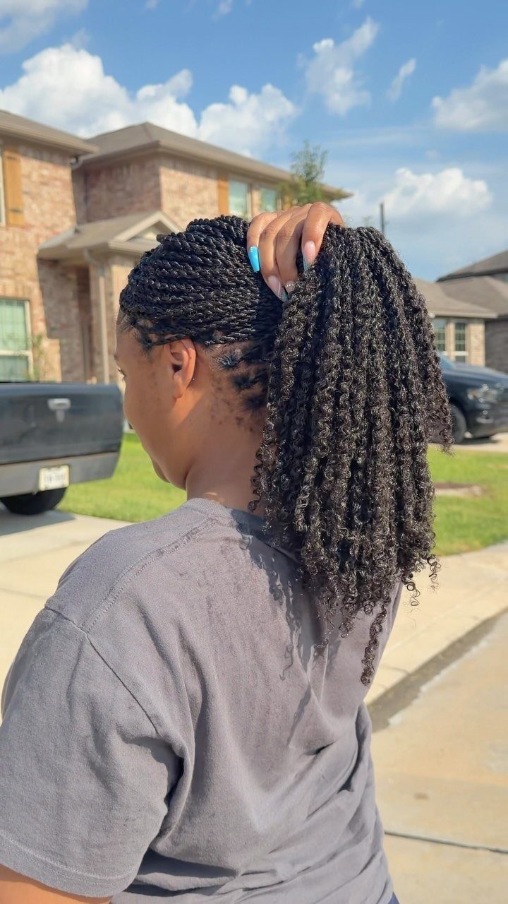Woman with dark passion twists styled into a high ponytail outdoors.