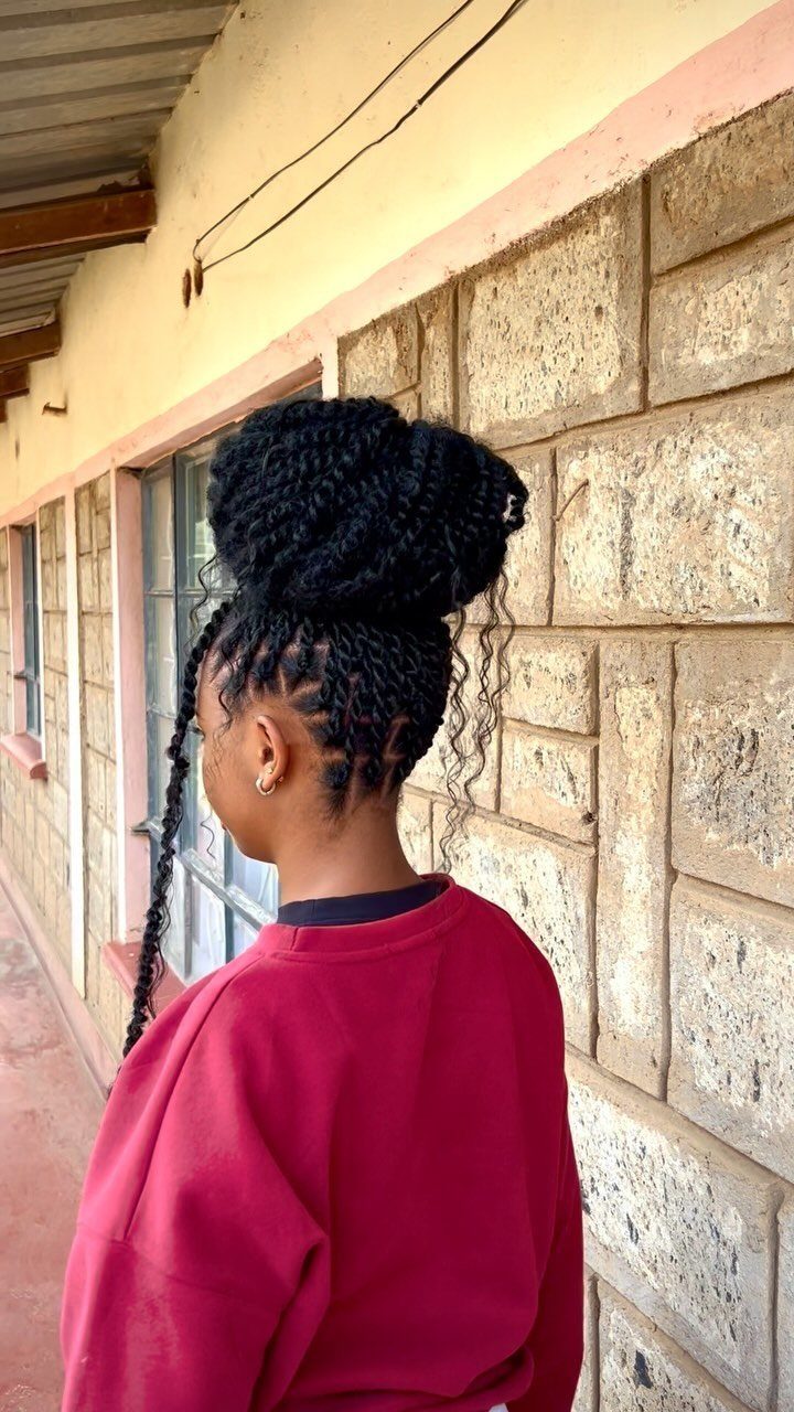 Black passion twists styled into a high bun updo on a person.
