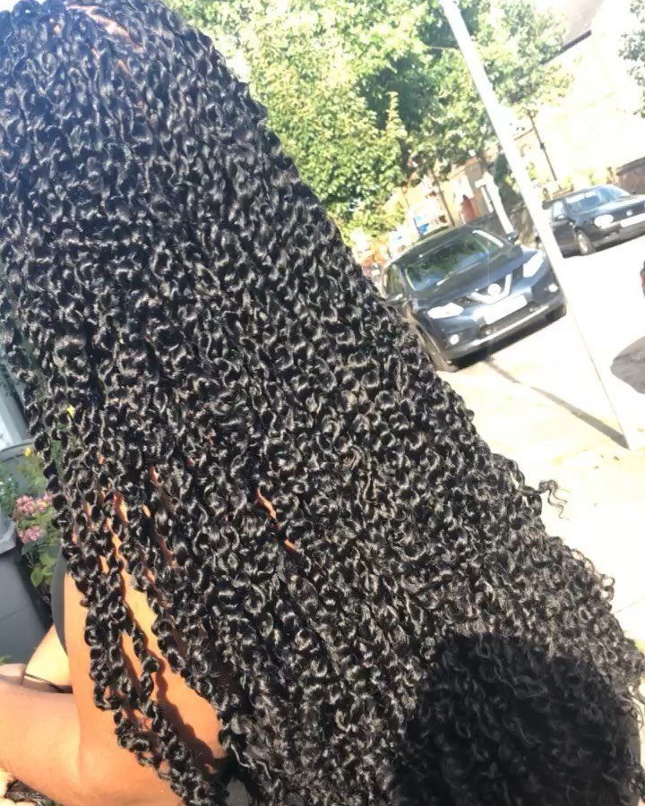 Long black passion twists with curly ends flowing down a person's back outdoors.