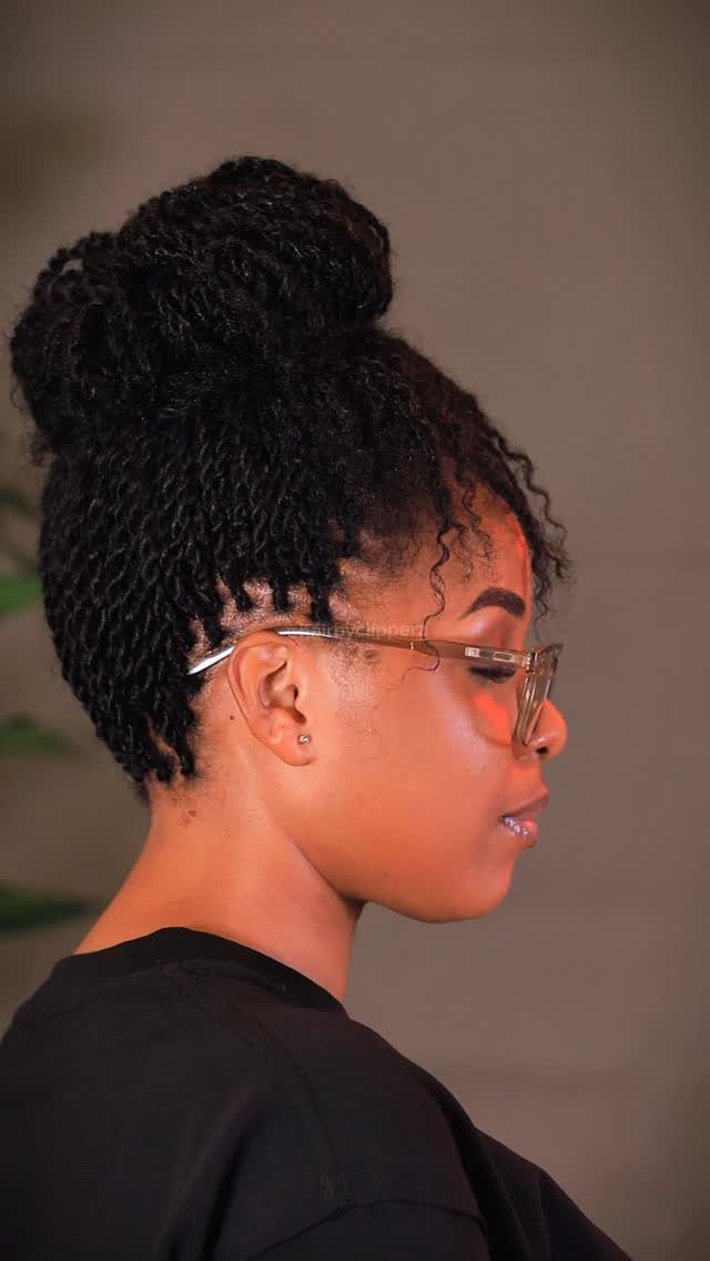 Woman with black passion twists styled into a high twisted top knot bun.