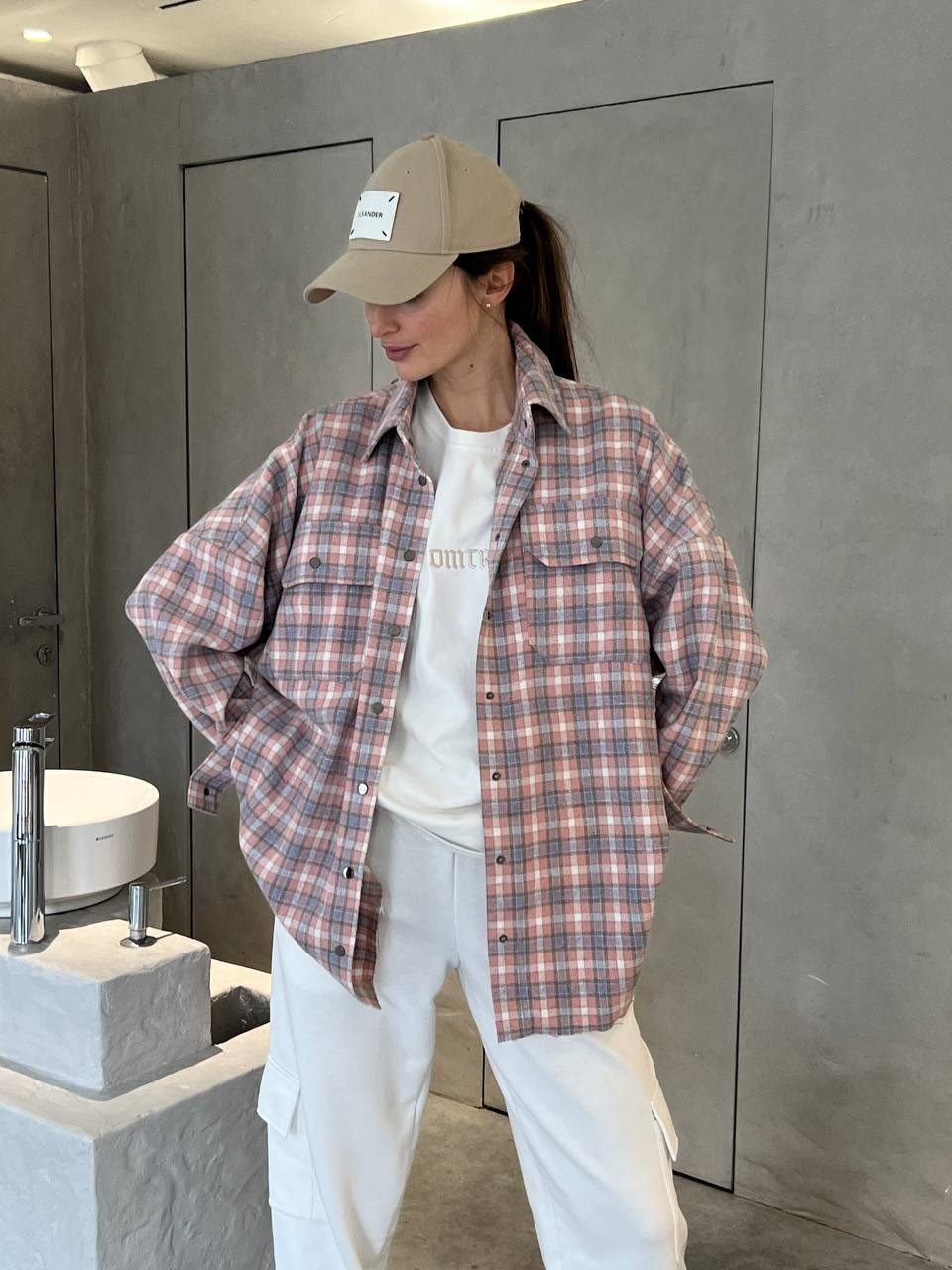 Woman in oversized pink plaid shirt, white t-shirt, and white cargo pants.