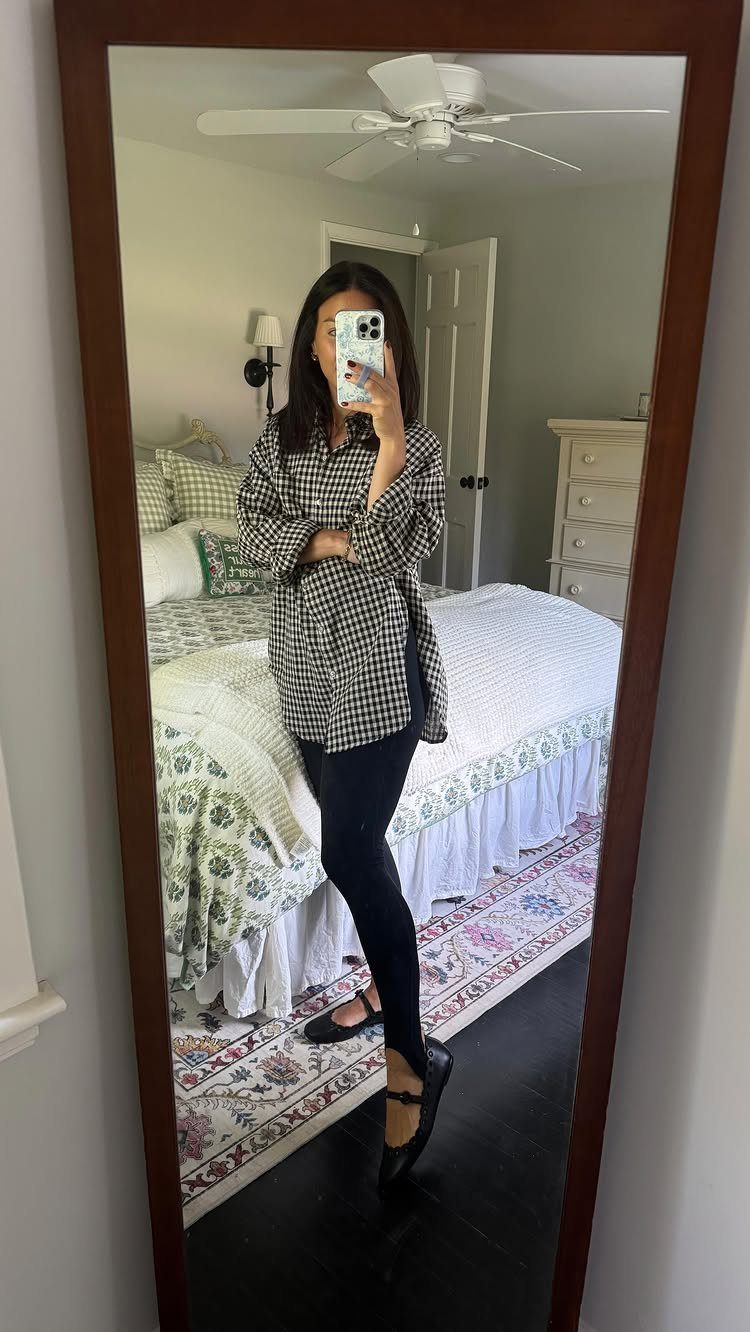 Woman in a black and white plaid shirt and black leggings taking a selfie.