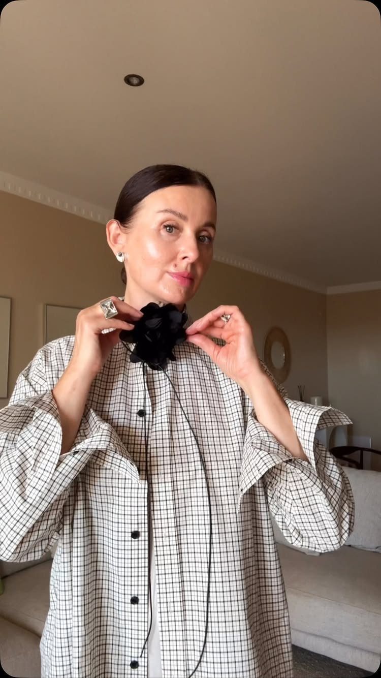 Woman wearing a white and black grid plaid shirt with a floral collar accessory.