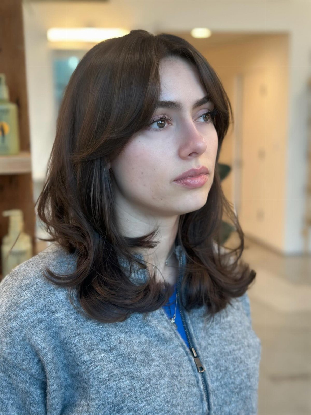 Woman with dark brown hair styled in voluminous feathered layers and curved ends.