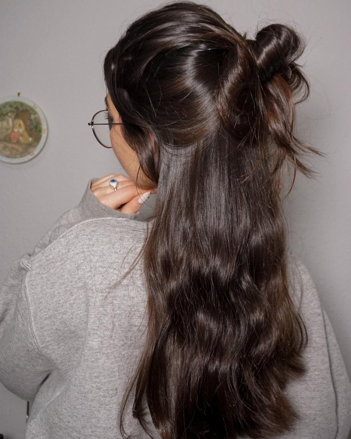 Woman with brown wavy hair styled in a half-up half-down messy bun.