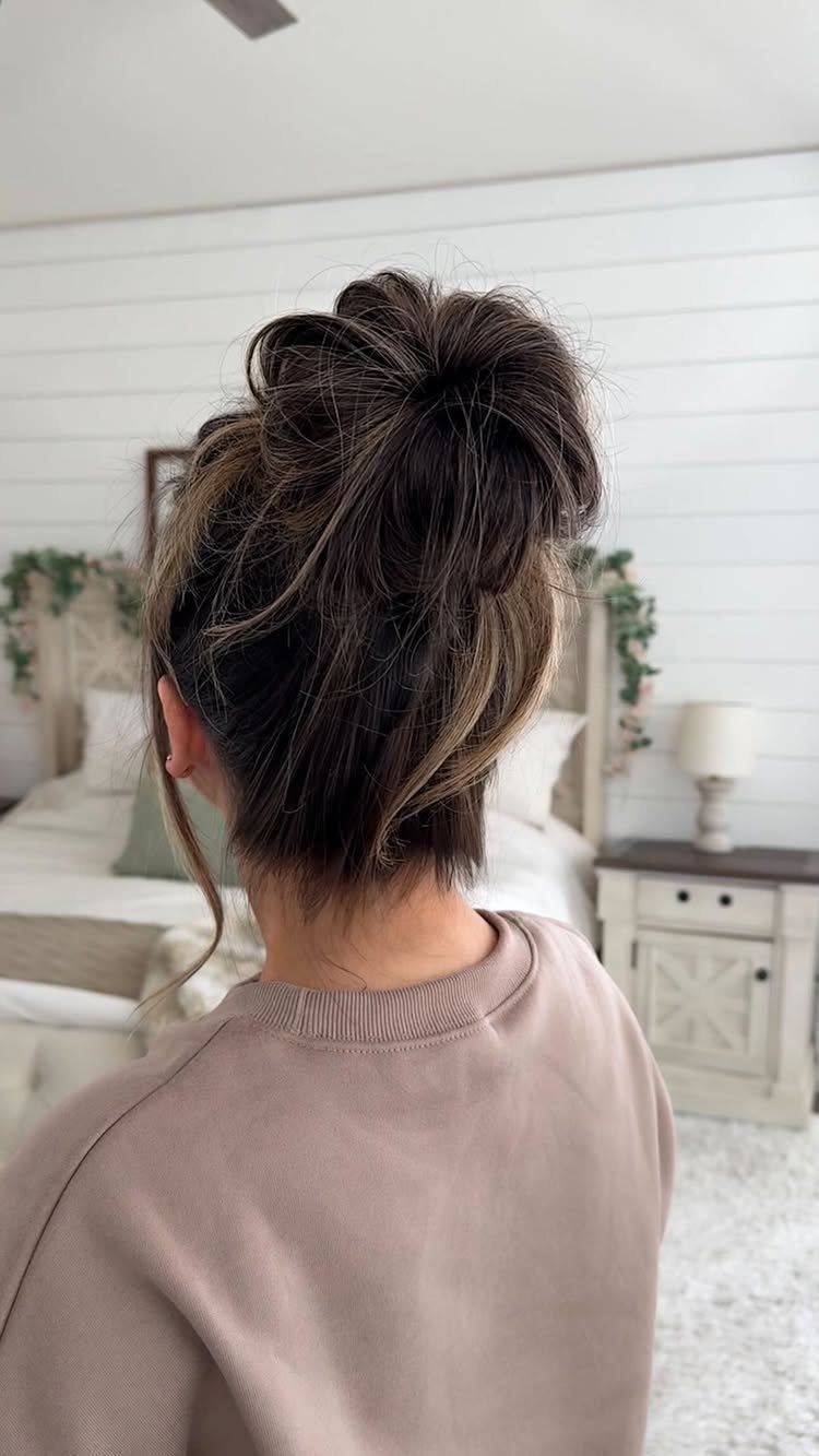 Woman with brown hair styled in a messy top knot bun from behind.