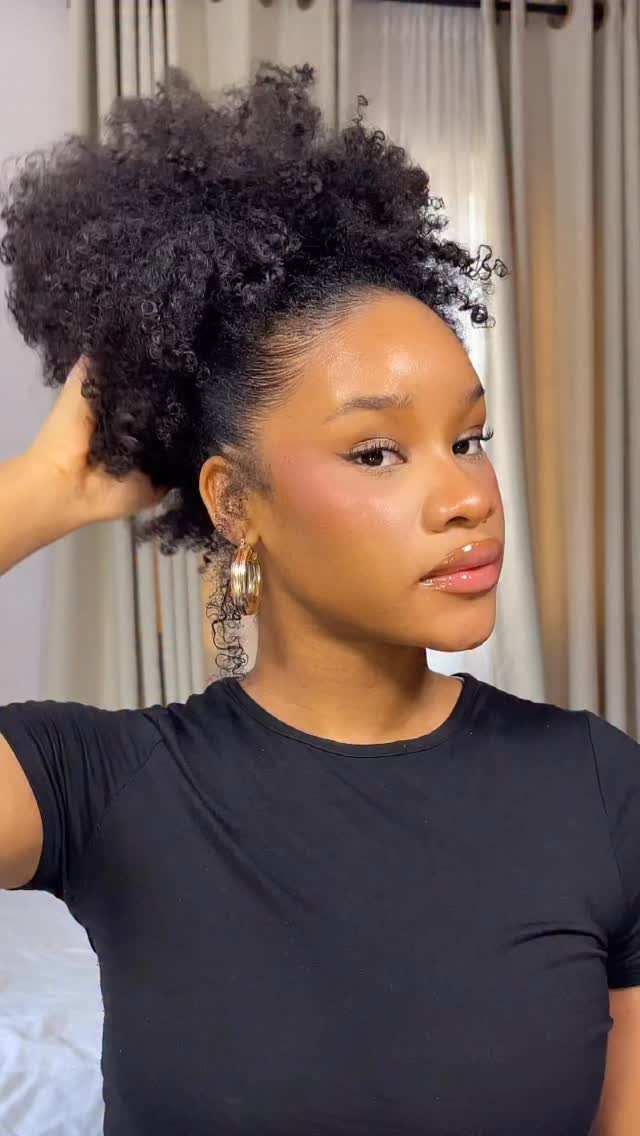 Woman with curly black hair styled in a high afro kinky puff.