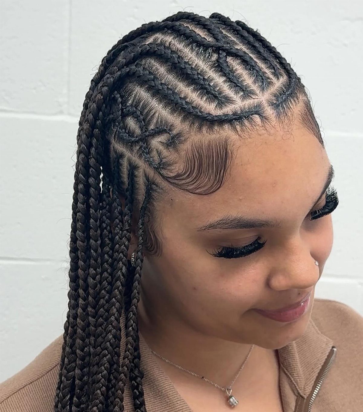 Woman with intricate cornrows transitioning into long braids and styled baby hairs.