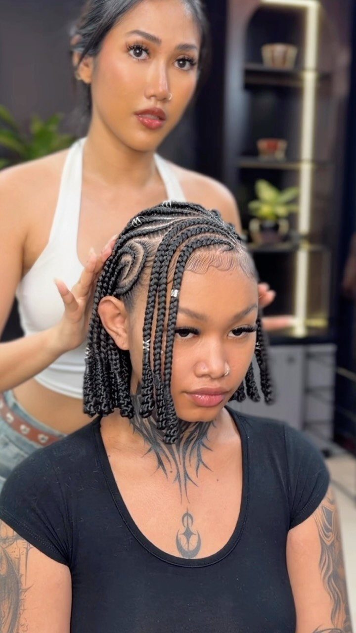 Woman with black Fulani braids and neck tattoos getting her hair adjusted.
