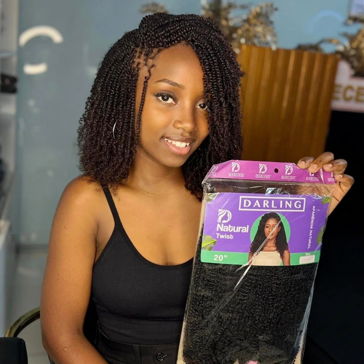 Woman with curly black passion twists holding a package of hair extensions.