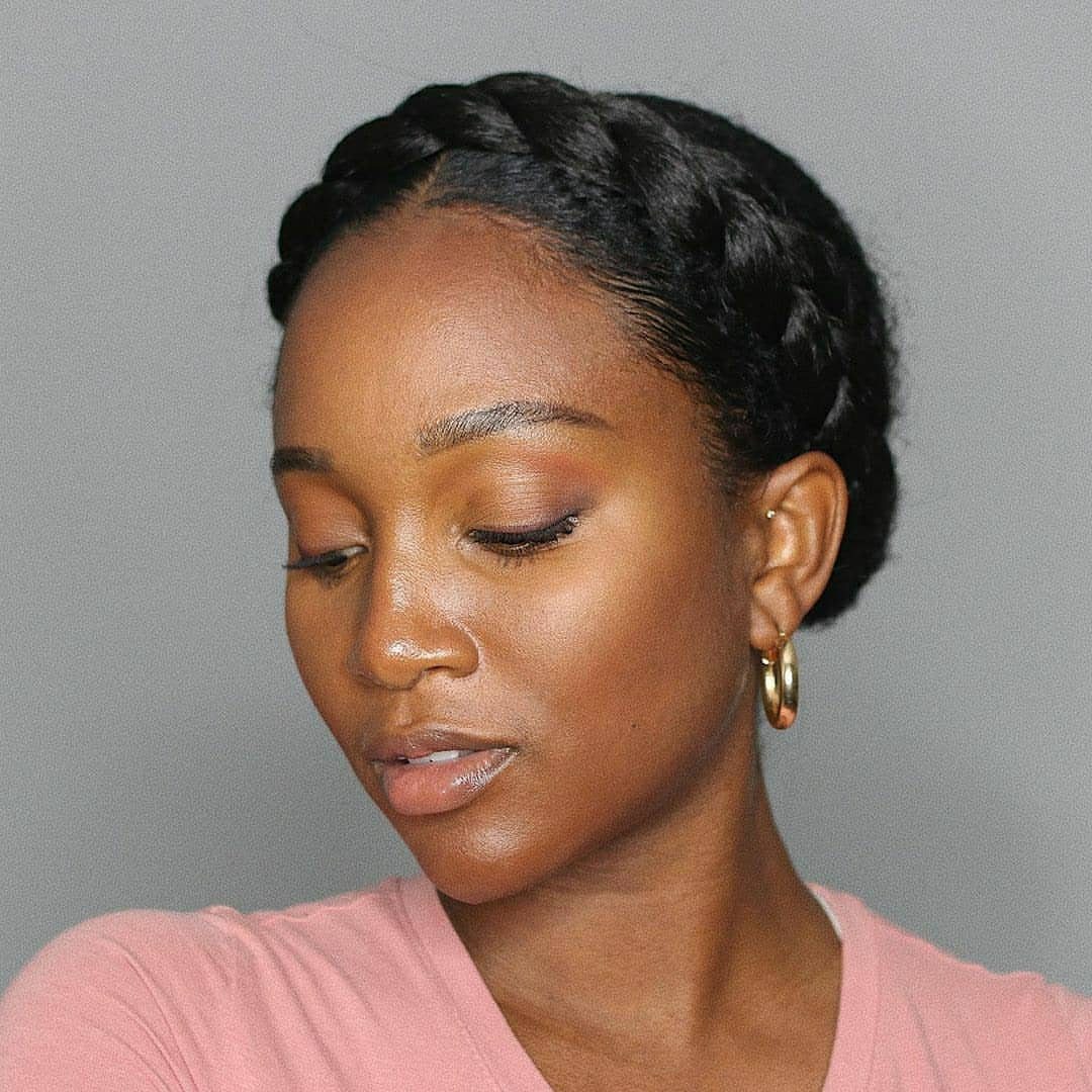 14 Protective Hairstyles with Braids and Twists to Try 6 Woman with a thick black braided crown hairstyle and gold hoop earrings.