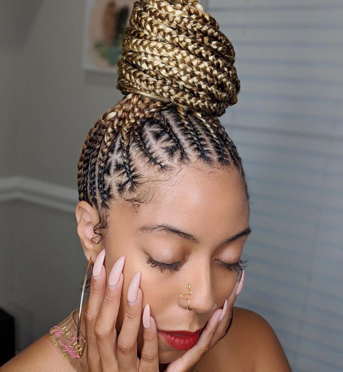 14 Protective Hairstyles with Braids and Twists to Try 10 Woman with blonde and brown braided hair styled into a high coiled updo.
