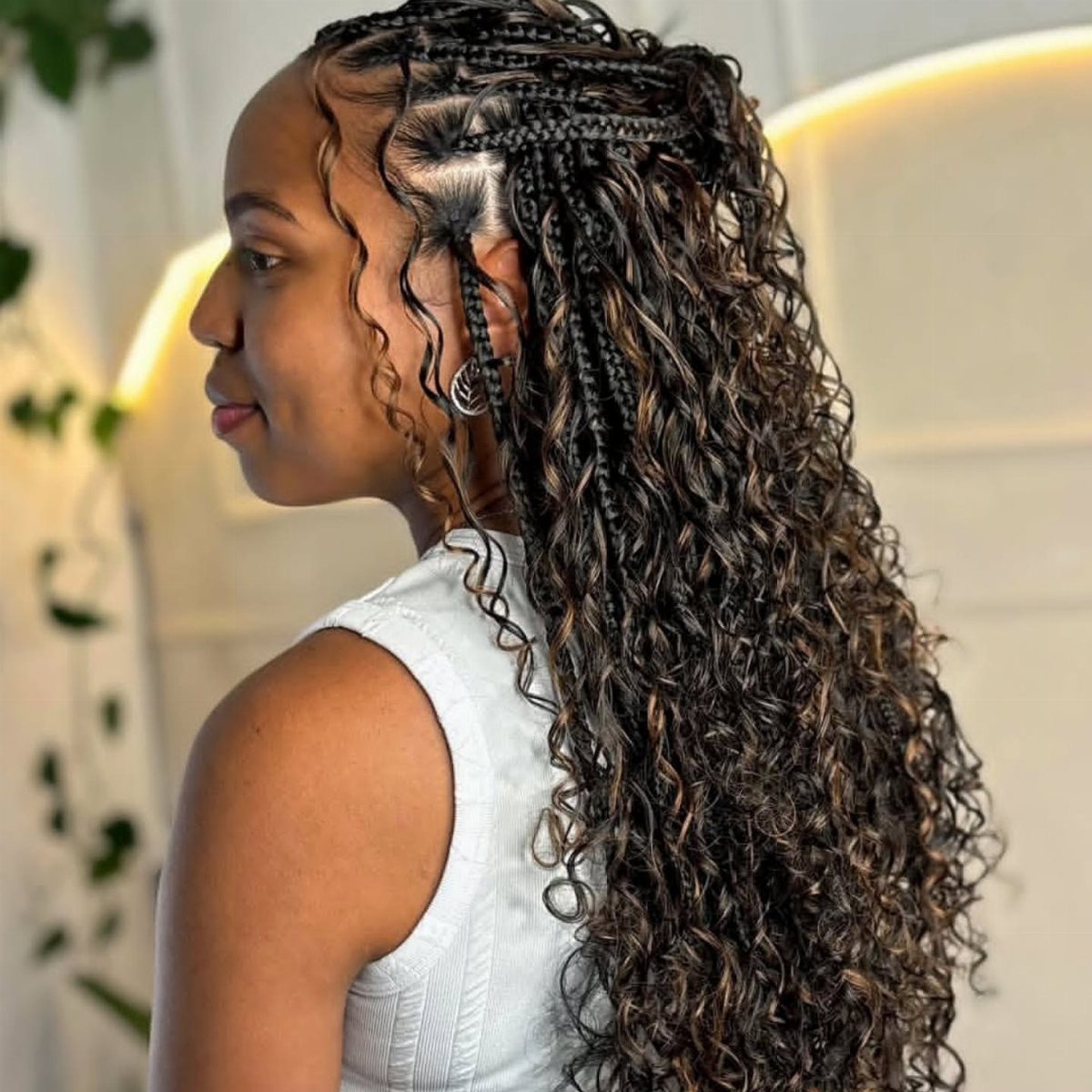 14 Protective Hairstyles with Braids and Twists to Try 9 Woman with long goddess braids featuring curly tendrils and cornrowed top sections.