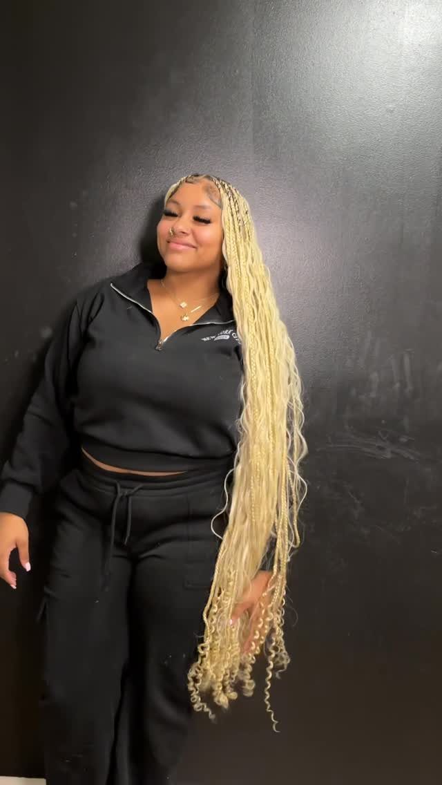 14 Protective Hairstyles with Braids and Twists to Try 3 Woman with long blonde knotless braids wearing a black athletic outfit against dark wall