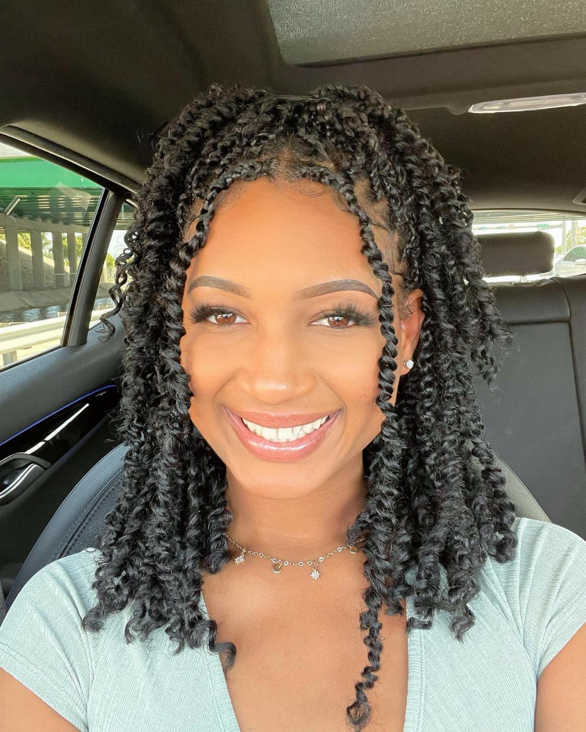 14 Protective Hairstyles with Braids and Twists to Try 12 Woman with shoulder-length black twists smiling while sitting in a car