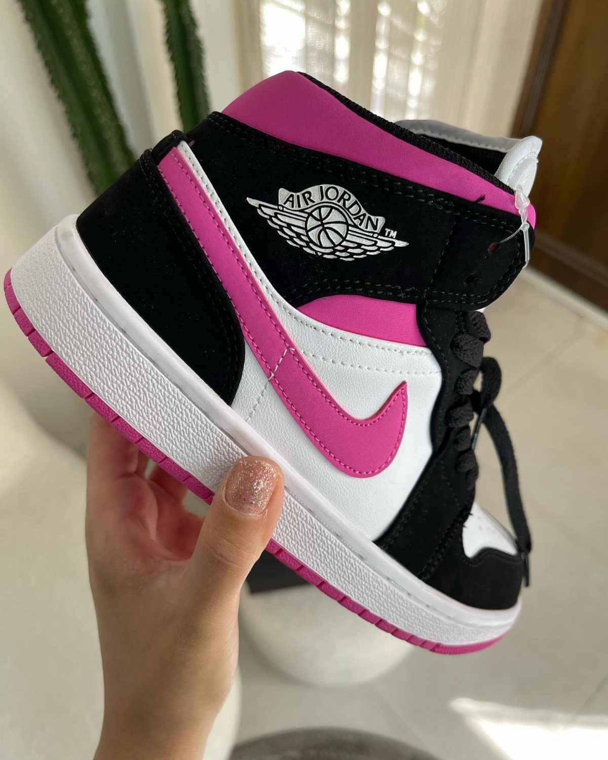 Nike Air Jordan 1 Mid sneaker in black, white, and bright pink colors.