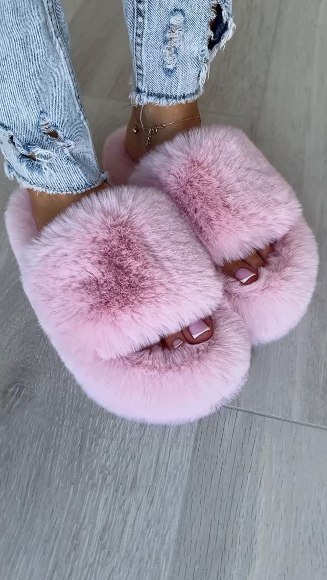 Pink fluffy faux-fur slide slippers worn with distressed light blue denim jeans.