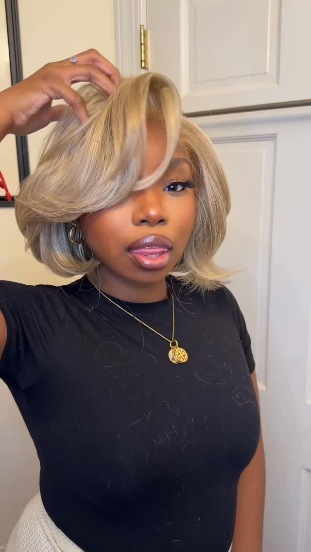Woman wearing an ash blonde chin-length bob wig with side-swept bangs.