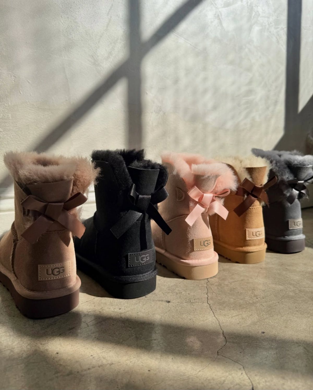 Short UGG Boots: 7 Outfit Ideas for Jeans, Skirts and Blazers 7 Five short UGG boots in various colors lined up on a concrete floor.