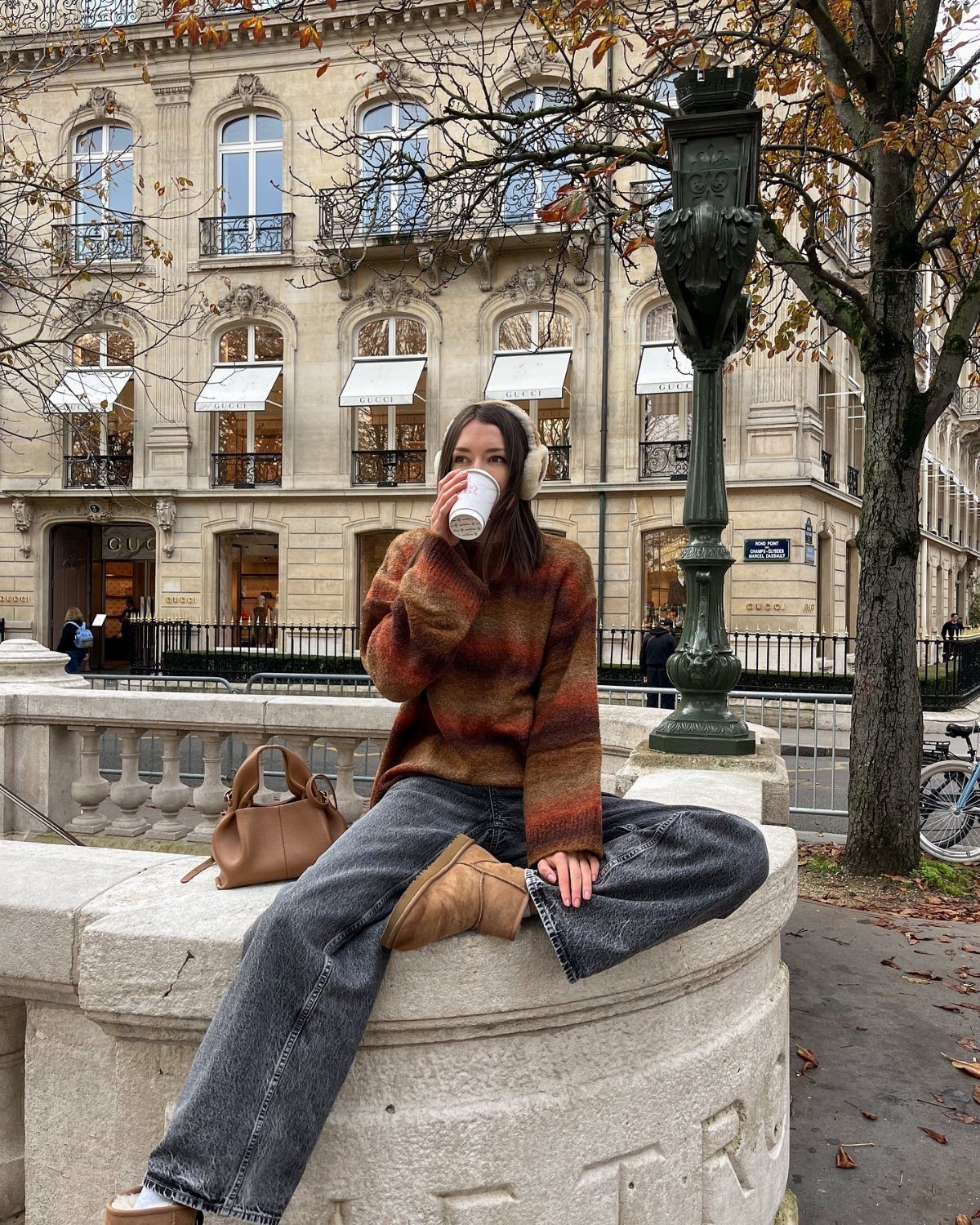 Short UGG Boots: 7 Outfit Ideas for Jeans, Skirts and Blazers 1 Woman wearing chestnut short UGG boots, grey jeans, and a striped sweater sitting outdoors.