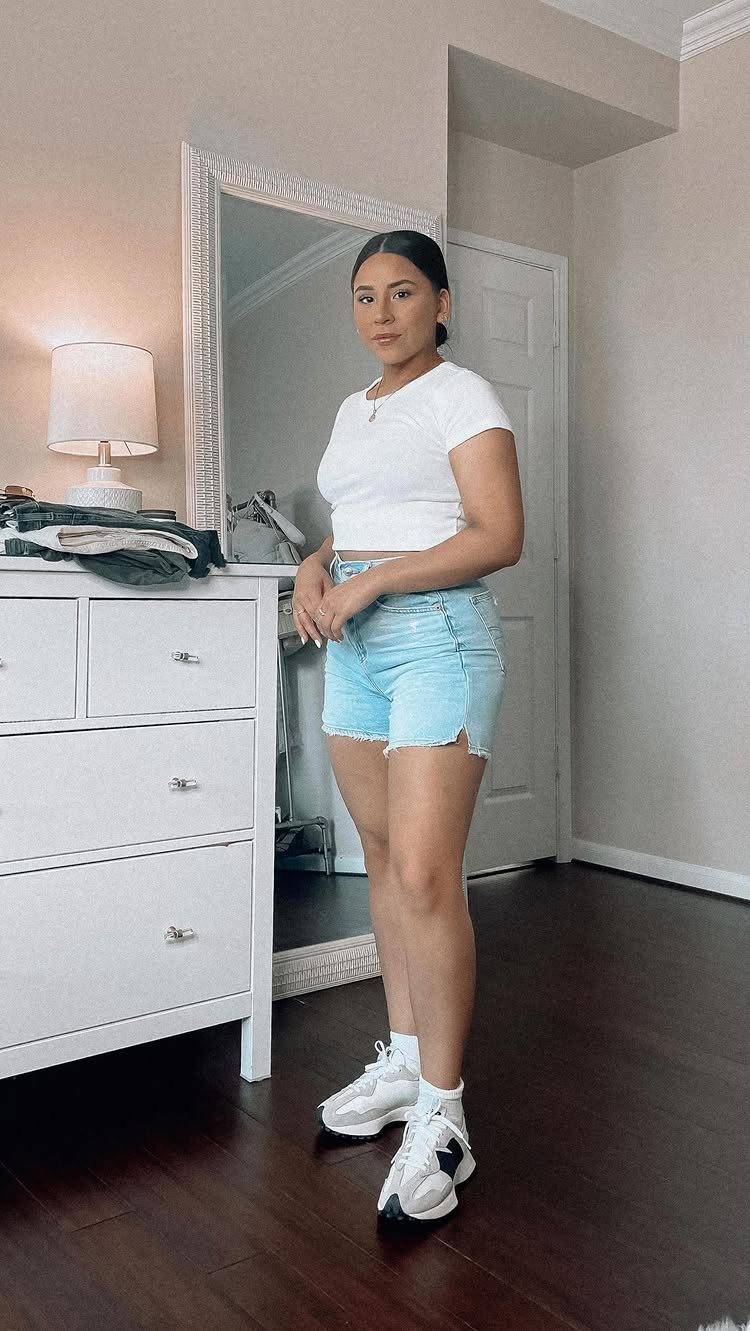 Sneakers to Wear With Shorts: 5 Ideas for Easy Summer Outfits 2 Woman wearing light blue denim shorts and white chunky sneakers in a bedroom