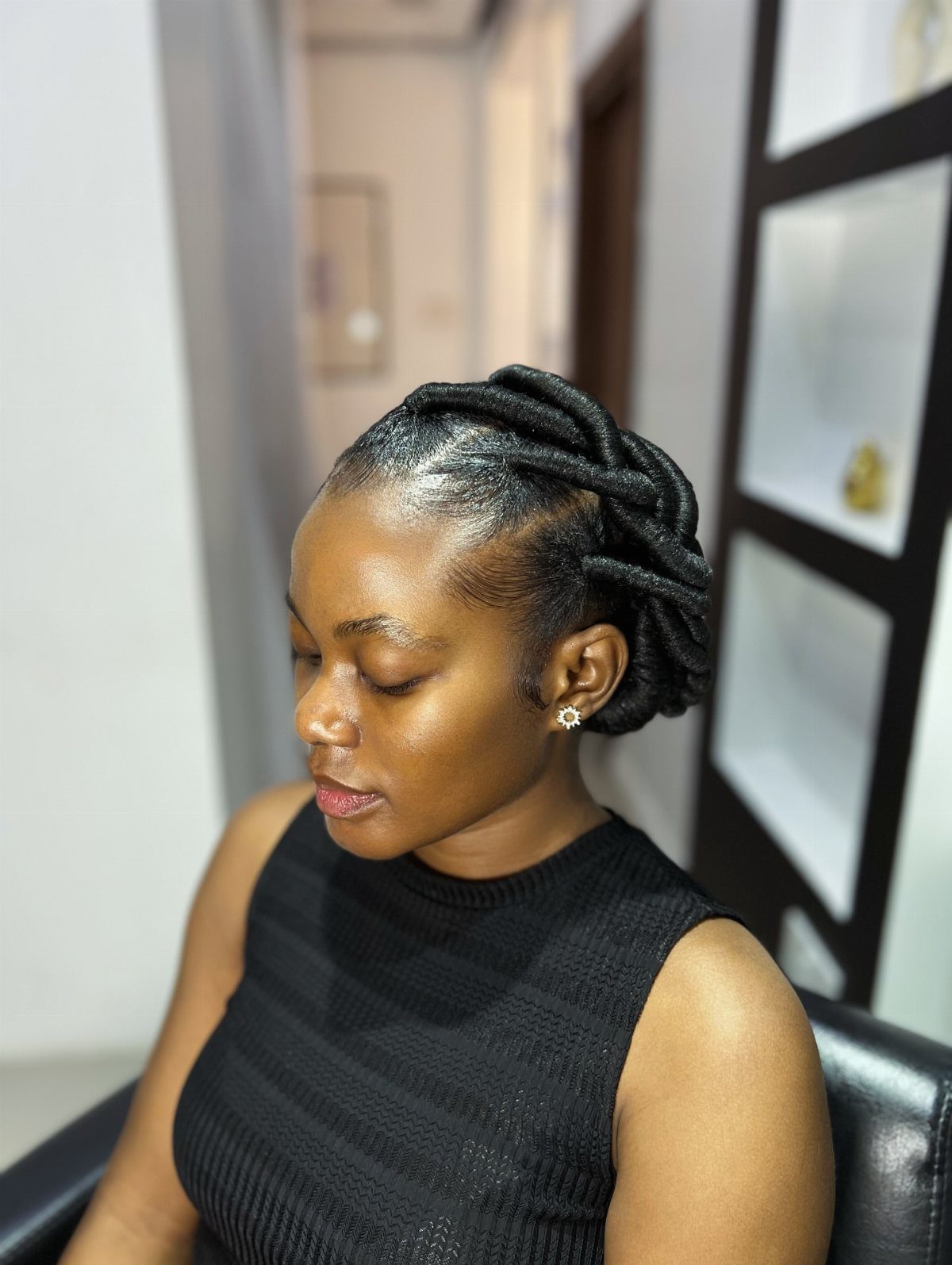 Woman with black hair styled in traditional African threading wrapped into a bun.