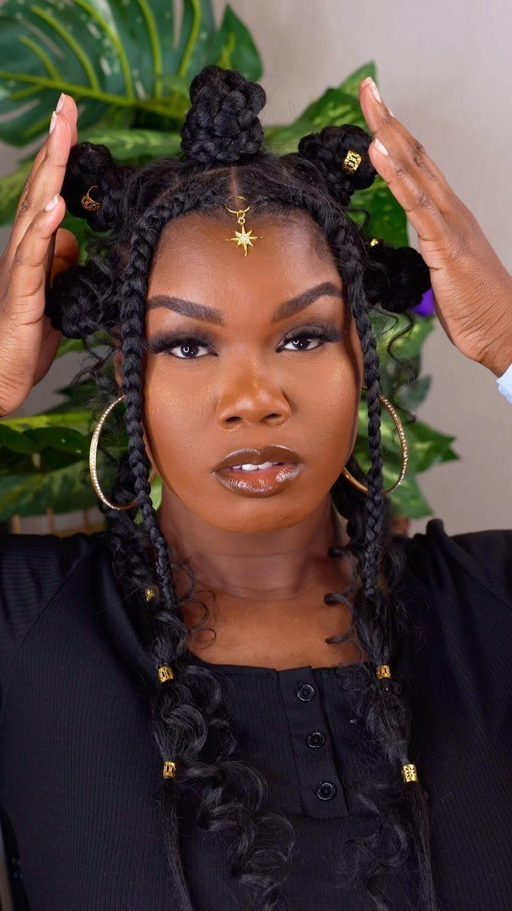 Woman with Bantu knots and long braids decorated with gold beads and jewelry.